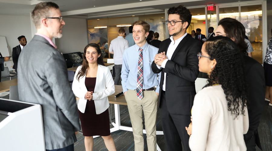 A group of Suffolk students meet with an employer partner during a client presentation.